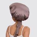 Person wearing a brown satin bonnet on a plain background